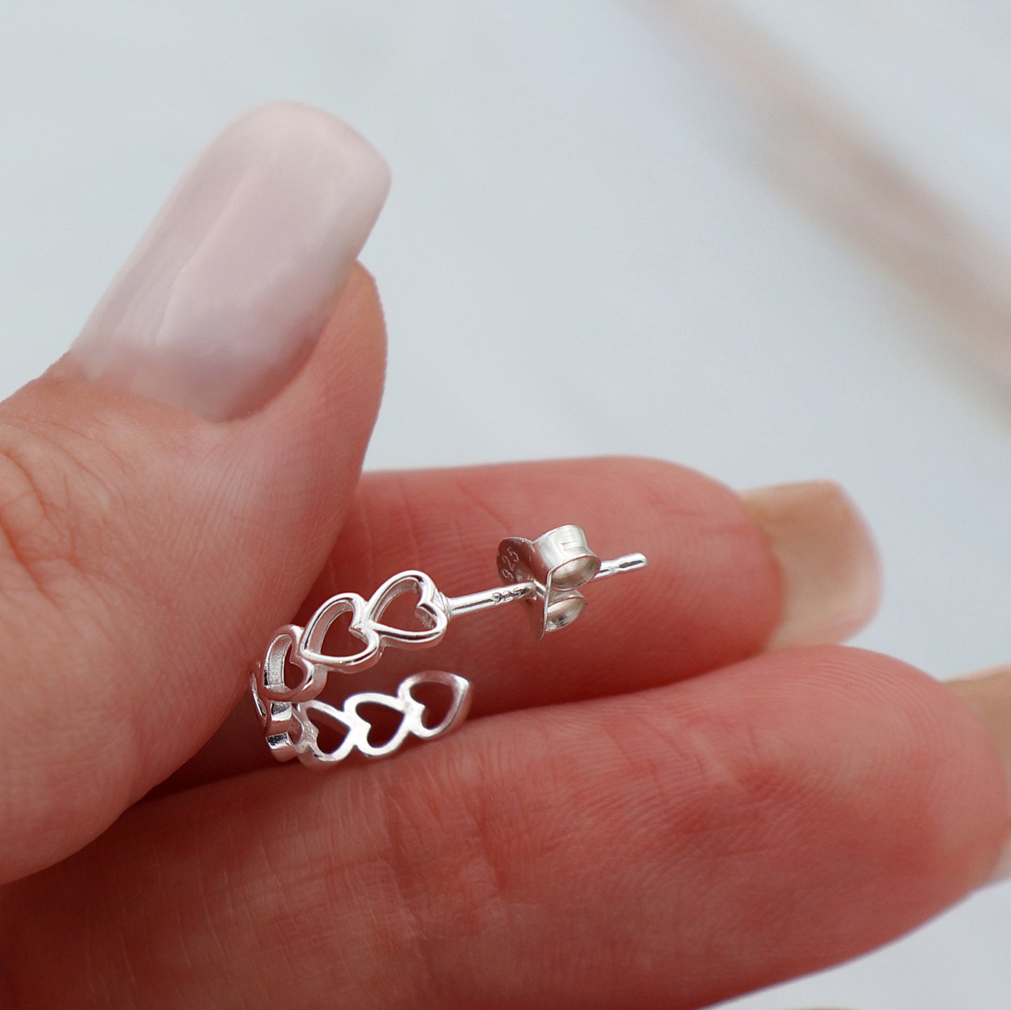 Stud earrings with hearts lined up in a semicircle shape