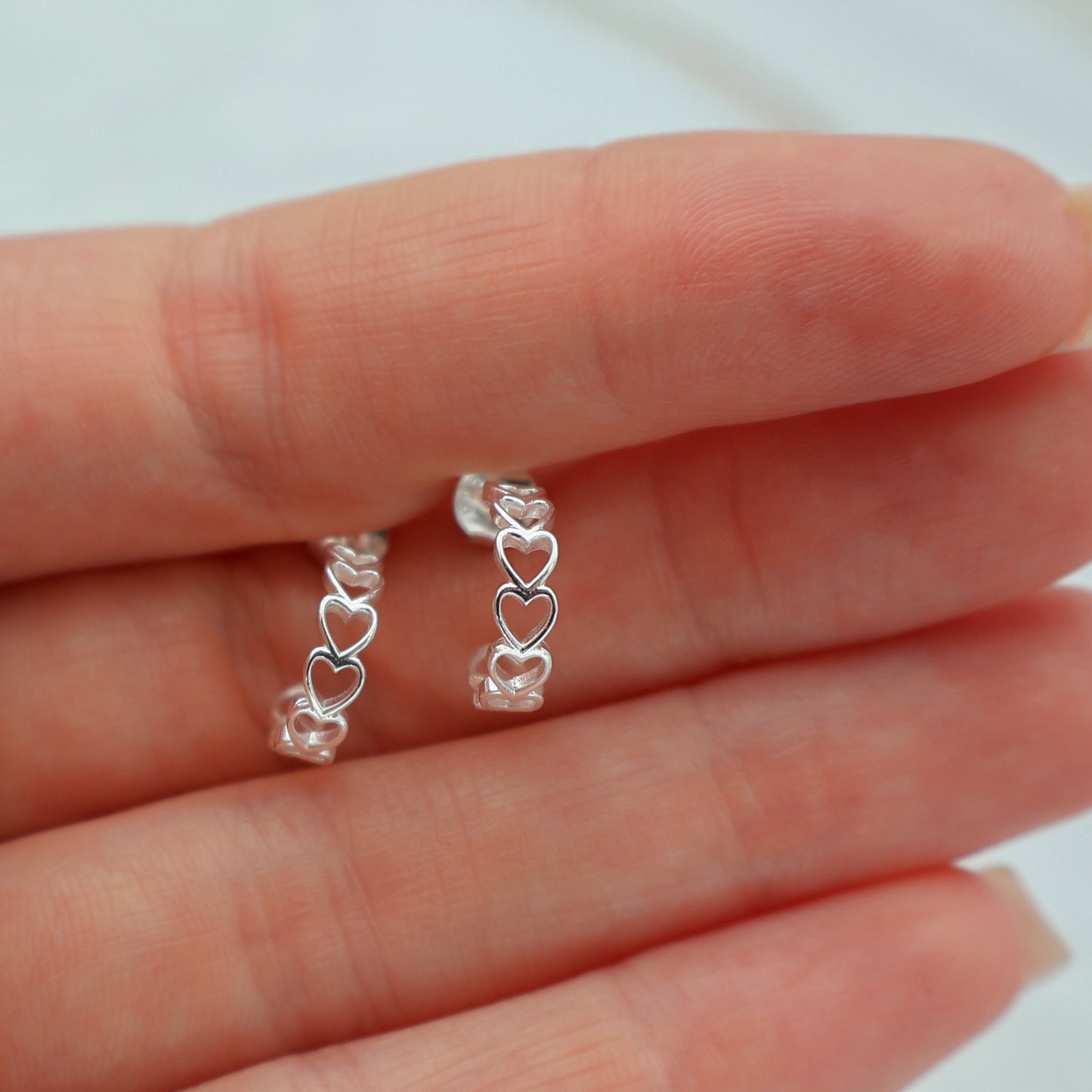 Stud earrings with hearts lined up in a semicircle shape