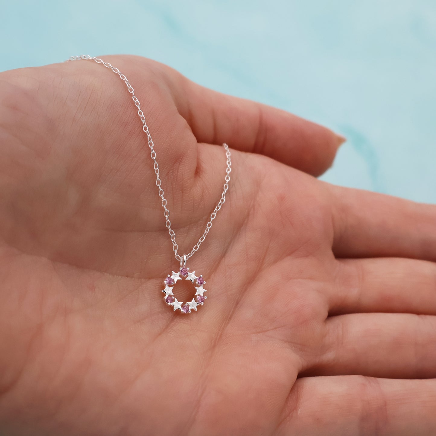 Necklace with a round pendant featuring stars and pink zirconia stones